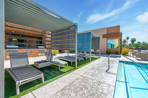 A modern outdoor pool area with a lounge chair and a table.