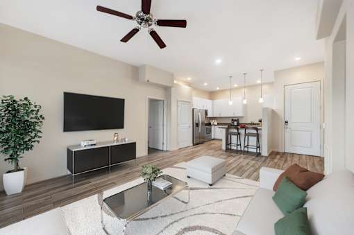 A modern living room with a flat screen TV, a coffee table, and a ceiling fan.