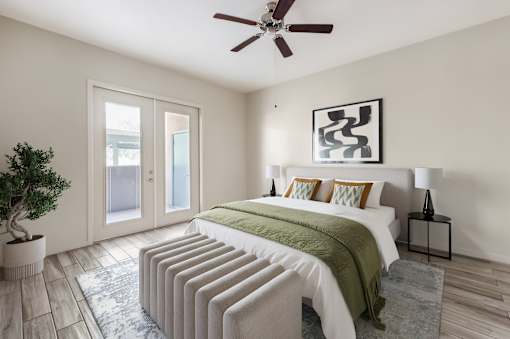 A bedroom with a bed, pillows, a ceiling fan, and a plant.