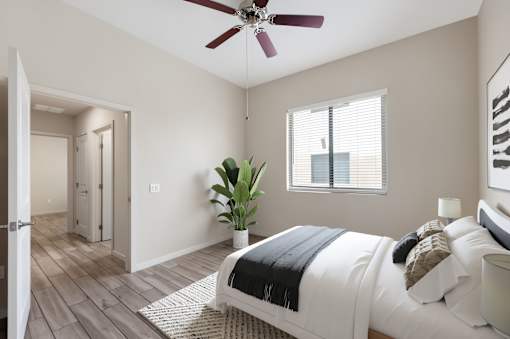 A bedroom with a bed, a ceiling fan, and a plant.