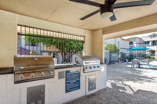 A patio with a grill and a fan.