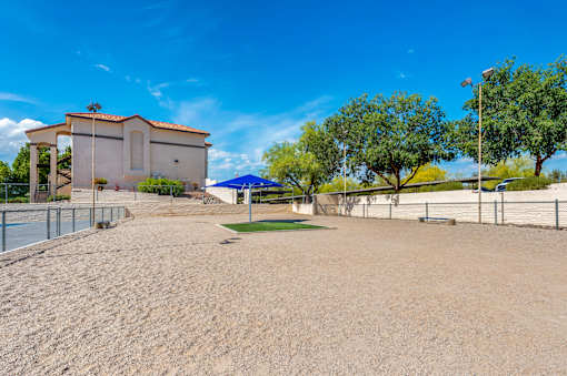 A sandy area with a building and trees in the background.