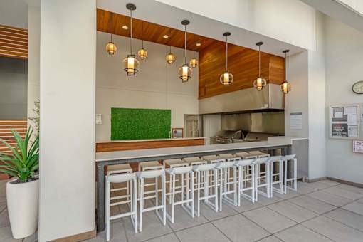 A row of white bar stools are arranged in front of a counter.