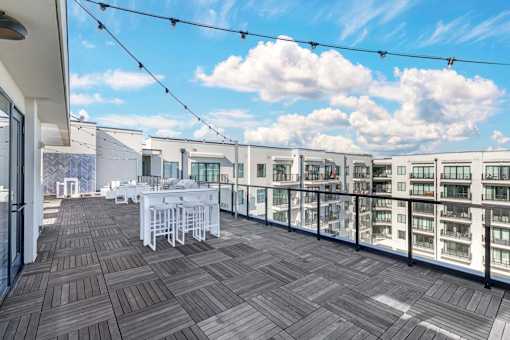 A balcony with a table and chairs overlooks a row of buildings.