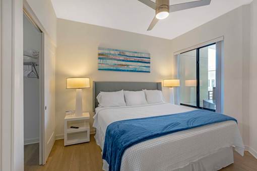 A bedroom with a bed, two lamps, and a ceiling fan.