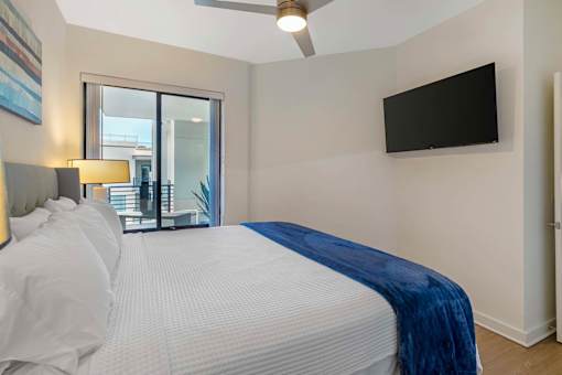 A bedroom with a large bed and a flat screen TV mounted on the wall.