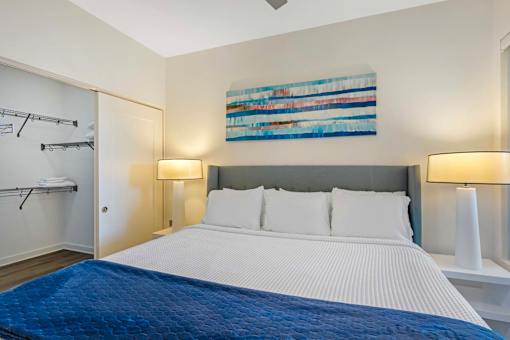 A bedroom with a large bed and a painting on the wall.