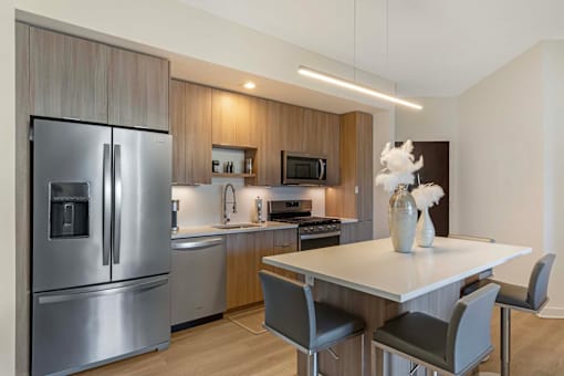 A modern kitchen with a refrigerator, sink, and dining table.
