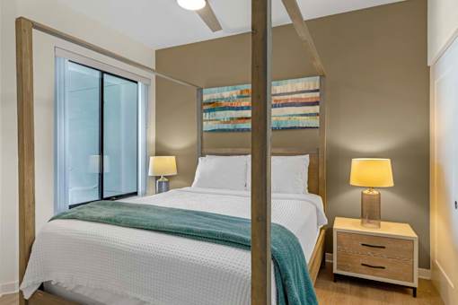 A bedroom with a bed, nightstand, and window.