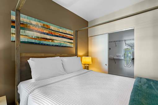 A bedroom with a large bed and a painting on the wall.