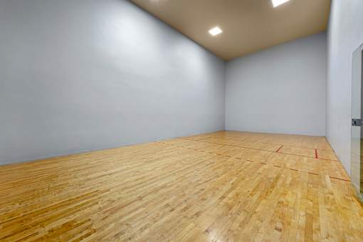 Indoor racquetball court with wooden floors and high ceilings
