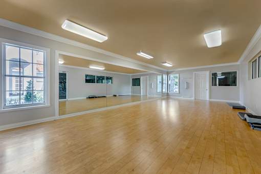 A spacious room with wooden floors and large windows.