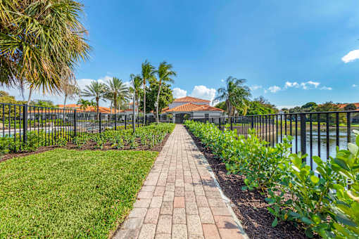 A walkway with a metal fence and green plants on both sides.