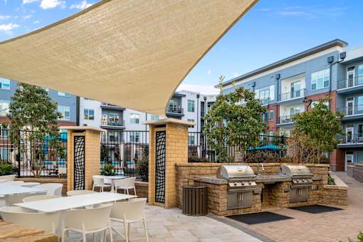 A patio with tables and chairs under a large shade structure.