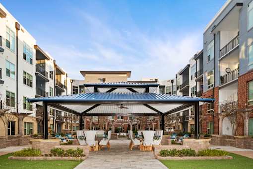 A patio with chairs and a table is surrounded by buildings.