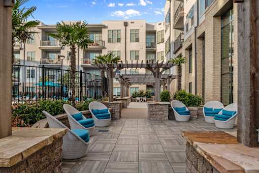 A patio area with chairs and a table with a view of apartment buildings.