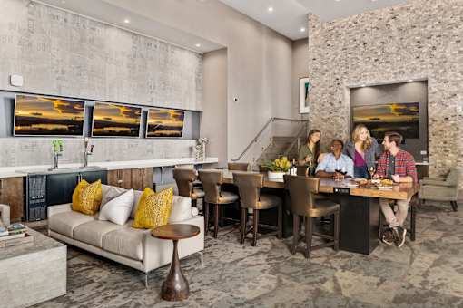 A group of people are sitting around a table in a room with a stone wall and pictures on the wall.