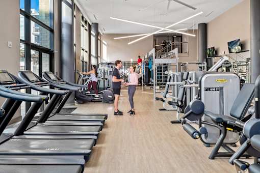 A gym with treadmills and people working out.