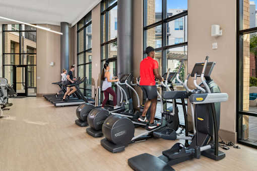 A gym with people working out on treadmilers and elliptical machines.