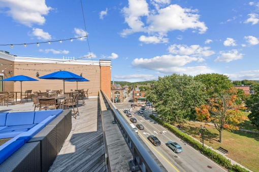 a rooftop patio with tables and umbrellas and a street with cars at The Merc, Waltham, 02453