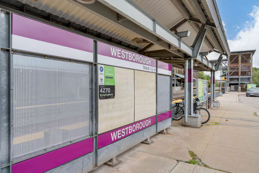 the entrance to a train station with a pink and white bus stop at Residences at Westborough Station, Westborough, Massachusetts