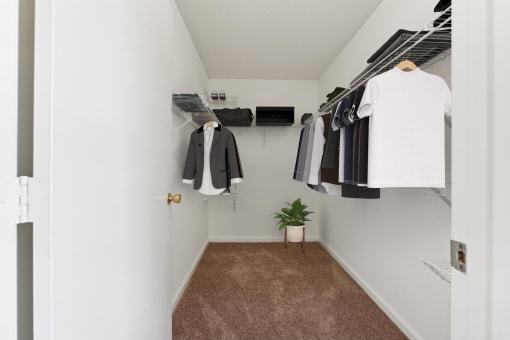 a walk in closet with clothes hanging on the wall and a door to the closet at Residences at Westborough Station, Massachusetts, 01581