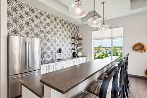A kitchen with a stainless steel refrigerator and a patterned backsplash.