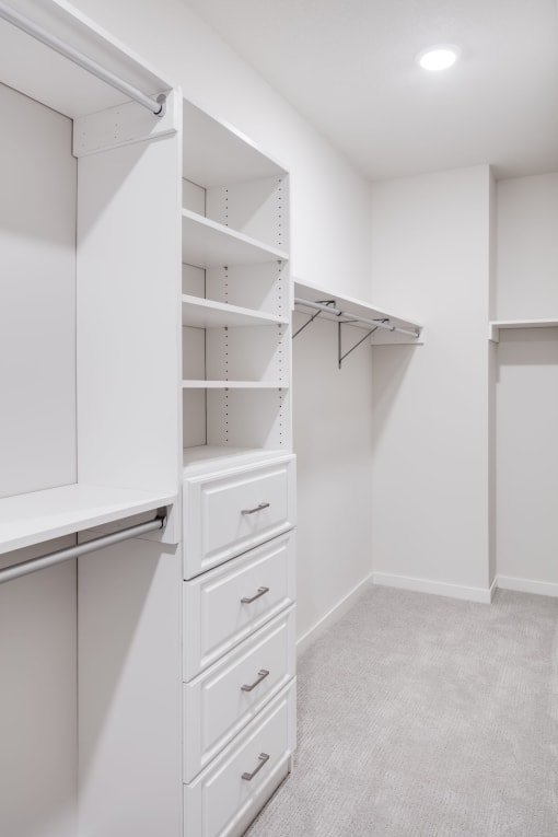 a spacious closet with white walls and drawers