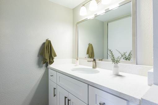 A white bathroom with a sink and mirror.