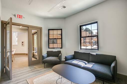 A black couch sits in a room with a round table in front of it.