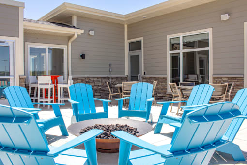 a patio with blue adirondack chairs and a firepit