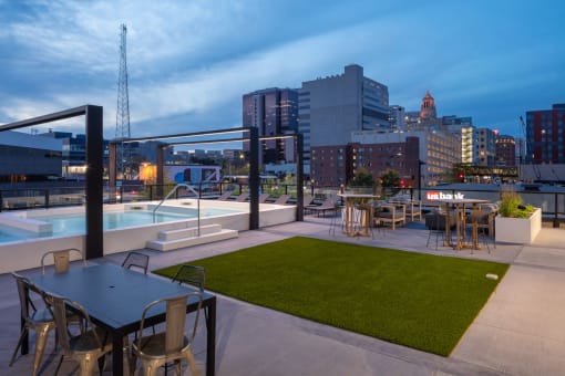 a rooftop patio with a pool and cityscape in the background