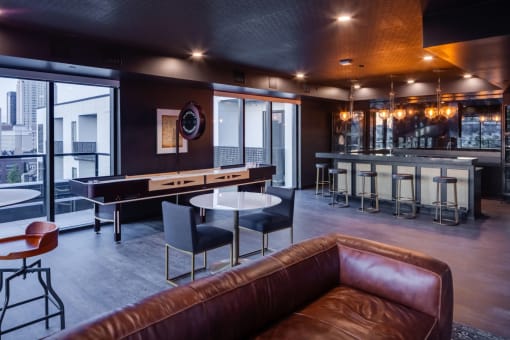 a living room with a brown leather couch and a bar with tables