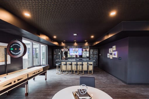 a bar in the clubhouse with a mirrored wall, tables and chairs