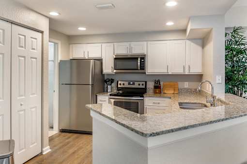 A kitchen with white countertops and stainless steel appliances at Floresta apartments in Jupiter, FL