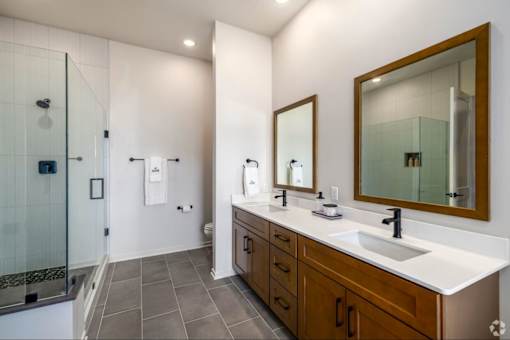A bathroom with a walk in shower, double sinks and a large mirror.