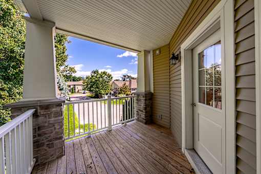 A wooden deck with a white door and a stone pillar.