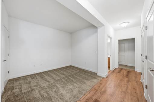 A room with a carpeted floor and wooden flooring.