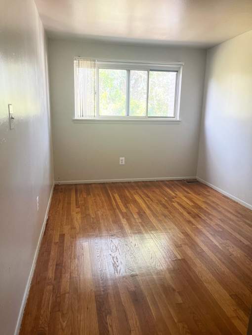 The second bedroom with a window and wooden floors.