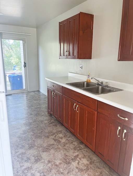 A kitchen with wooden cabinets and a double sink
