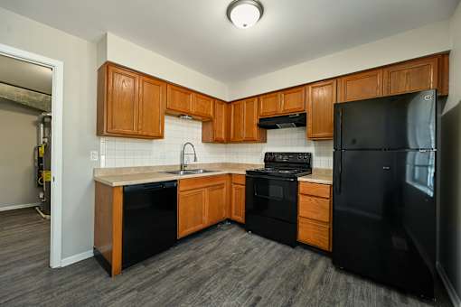 A kitchen with black appliances and wooden cabinets.