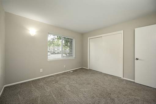 A room with a carpeted floor and a window with blinds.
