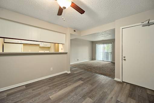 A room with a ceiling fan and wooden flooring.