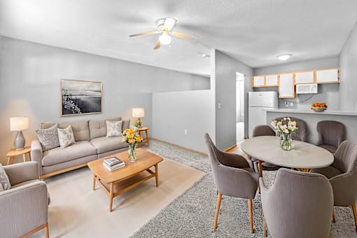 A living room with a grey couch, a coffee table, and a dining table with chairs.