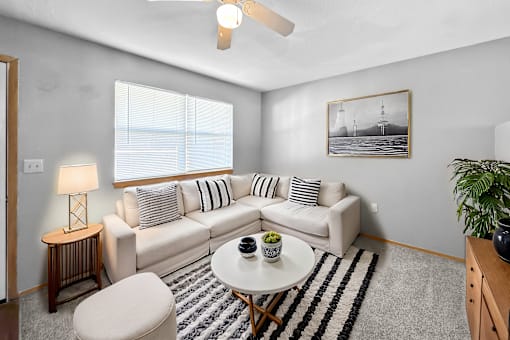 A living room with a white couch, a small table, and a ceiling fan.