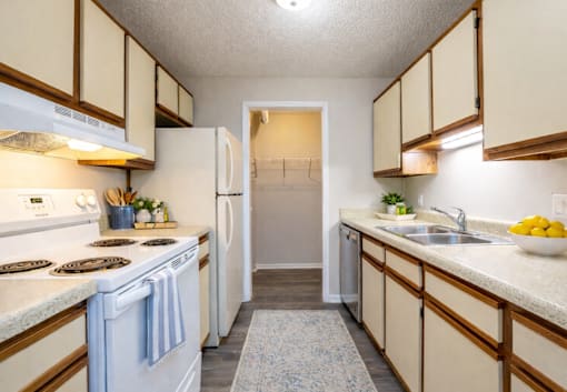 A kitchen with white appliances and wooden cabinets.