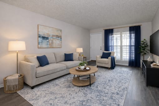 A living room with a beige couch, a coffee table, and a painting on the wall.