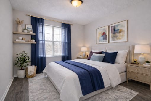 A bedroom with a large bed, a window with blue curtains, and a painting on the wall.