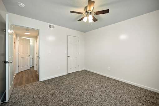 A room with a ceiling fan and carpeted floor.