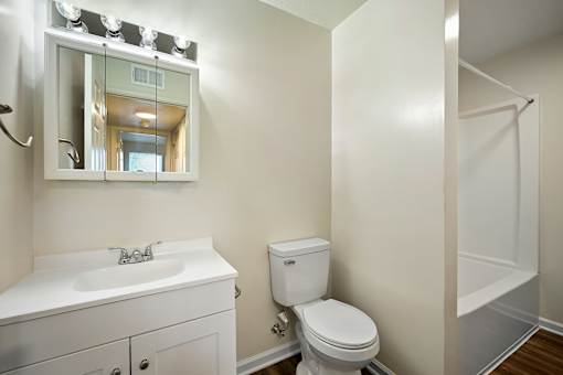 A white bathroom with a toilet, sink, and mirror.